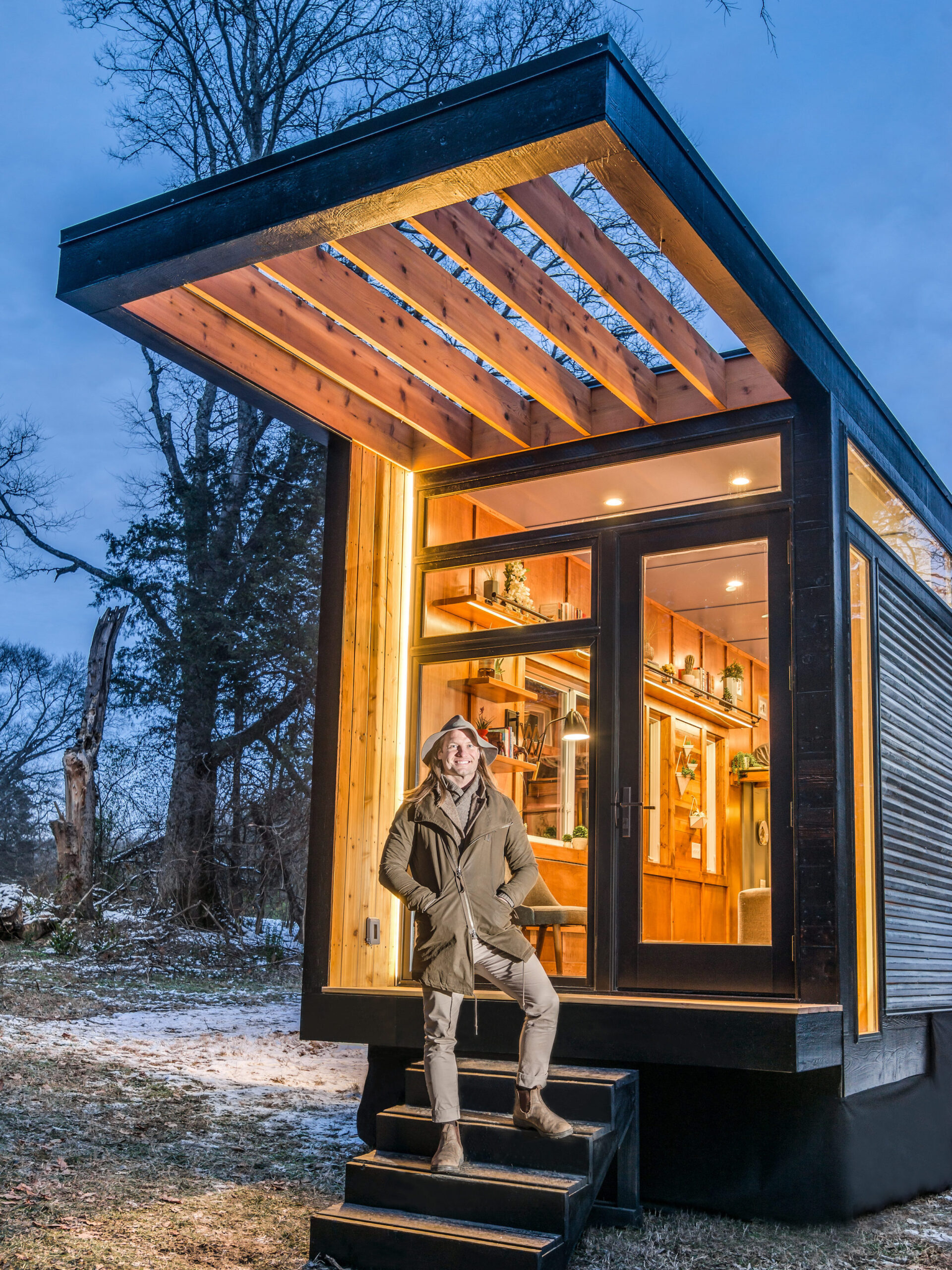 A New Frontier tiny home with a model standing outside the door.
