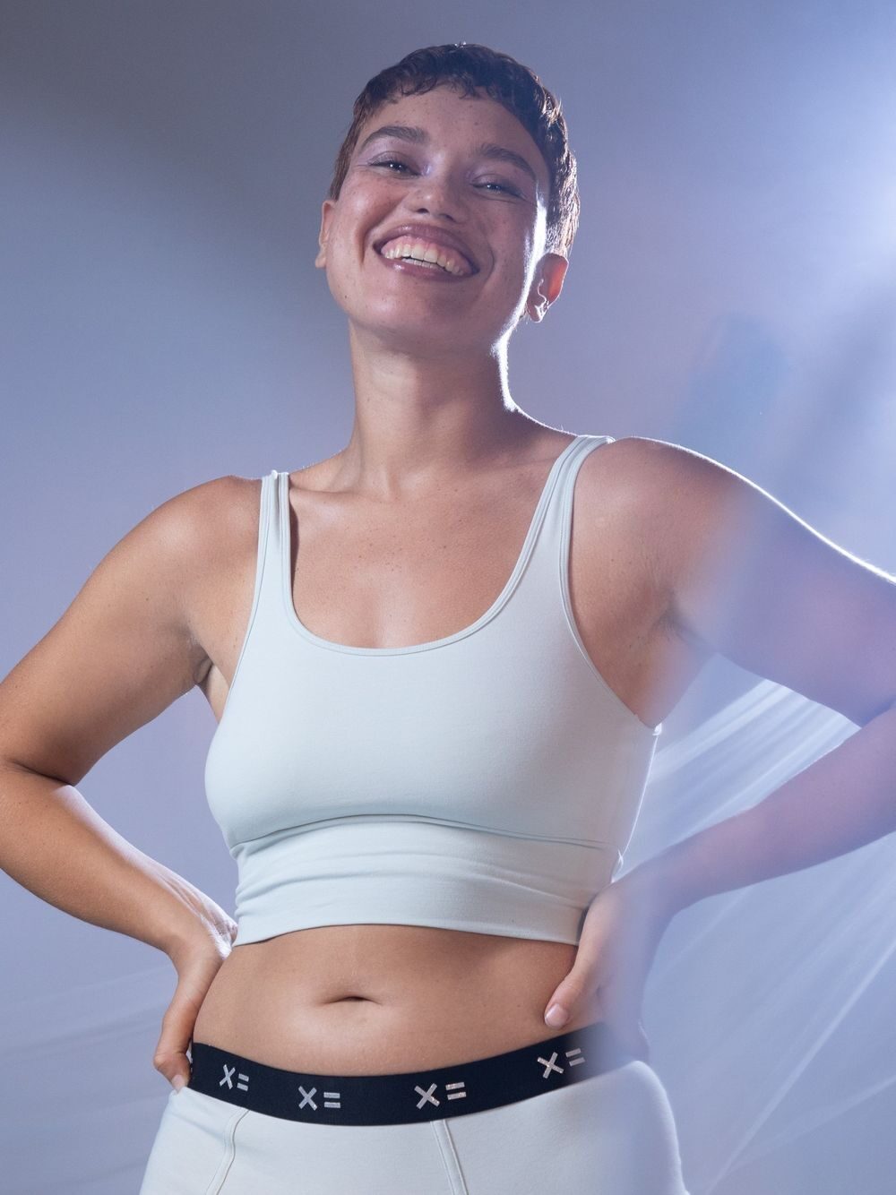 Studio shot of a model wearing a Tomboy X activewear bra and underwear set in a light blue shade.