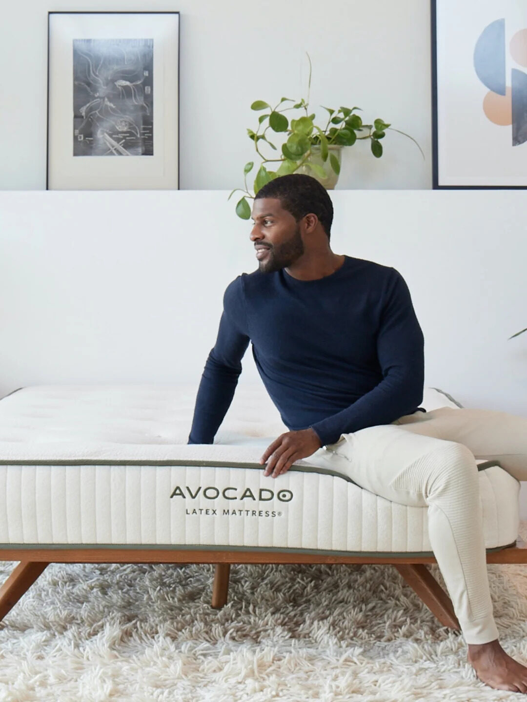 A model seated on an Avocado mattress.