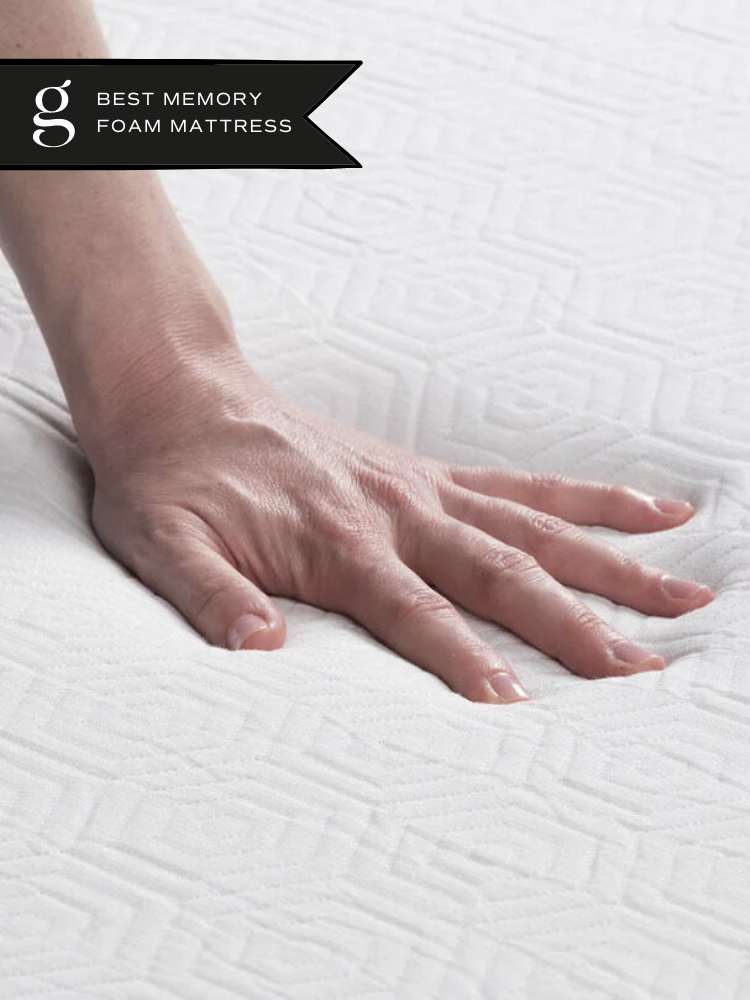 A hand pushes into a Bear eco friendly memory foam mattress. The Good Trade 'Best Memory Foam Mattress' sticker is in the top left corner.