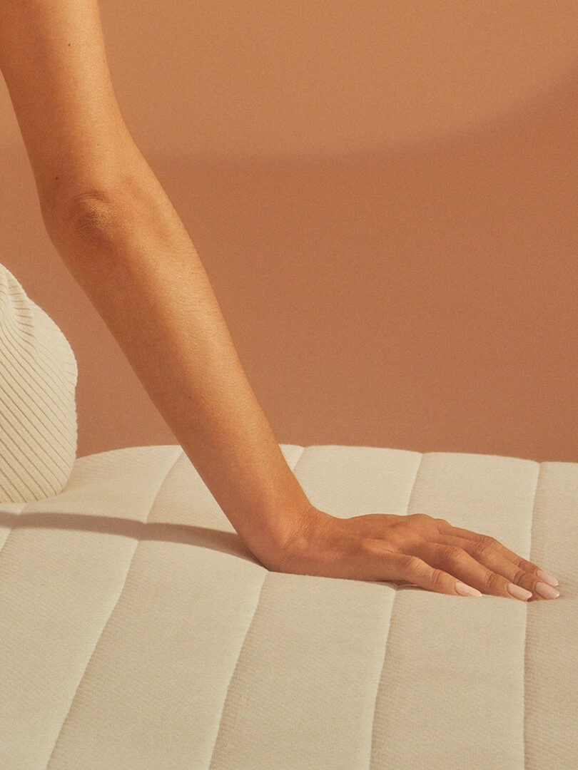 A close up shot of a hand placed on an Earthfoam mattress.