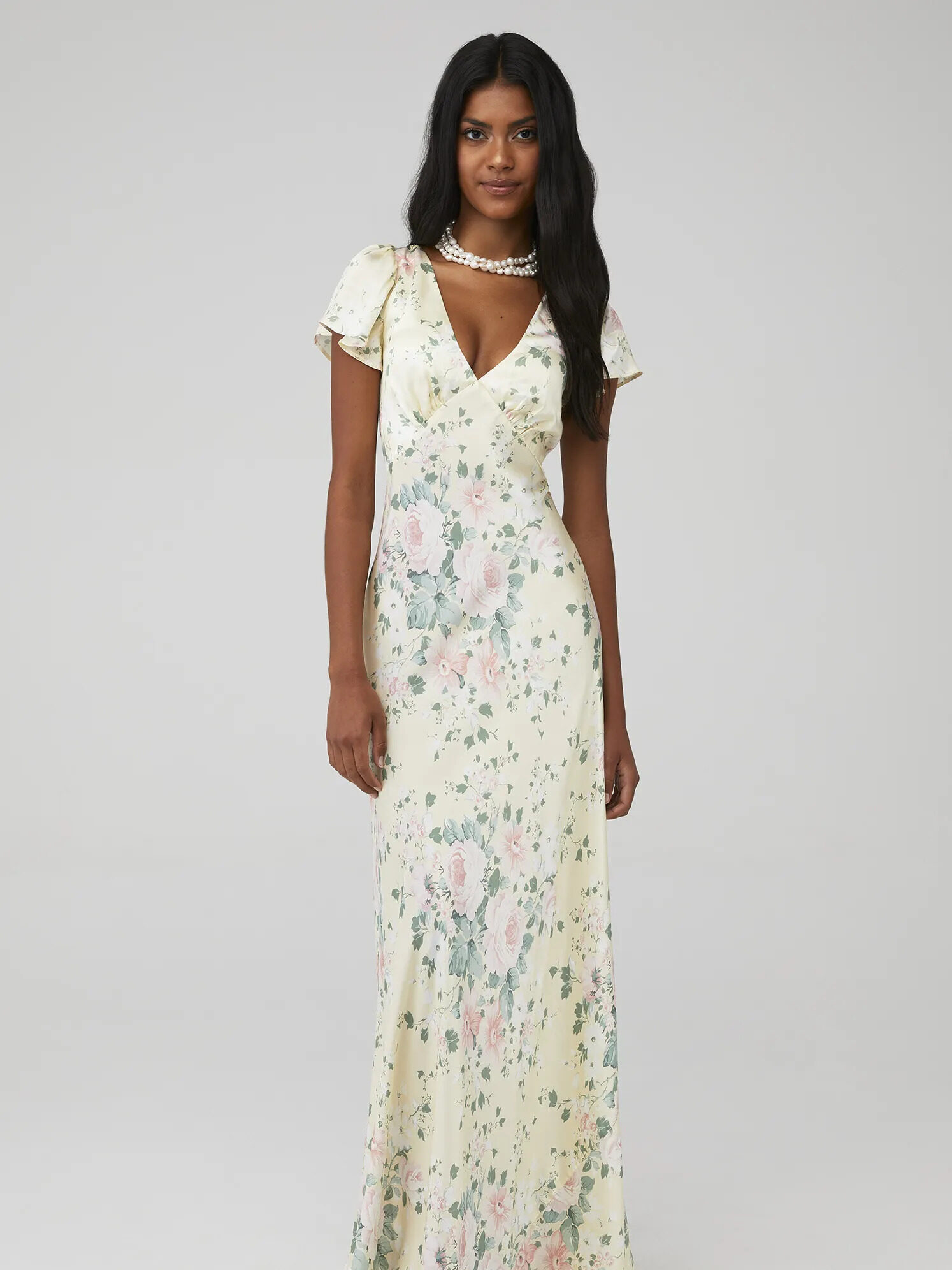 A model wearing a white cap sleeve maxi dress with blue and pink florals from FashionPass.