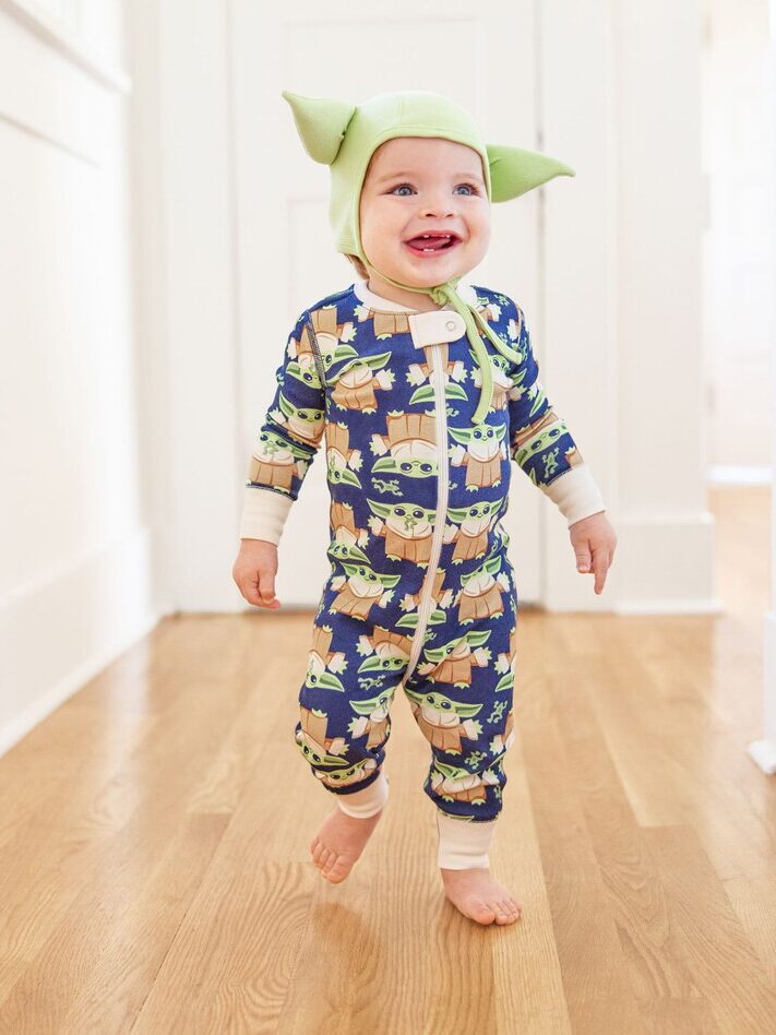 A baby wearing a patterned Yoda long sleeve onesie by Hanna Andersson.
