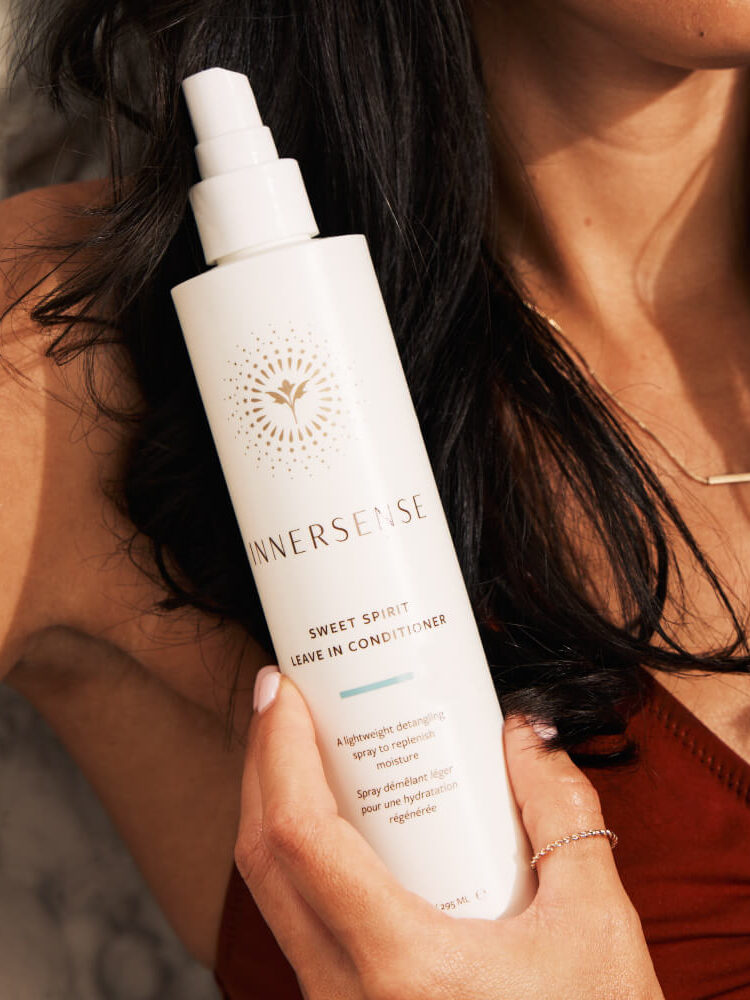 A model holding up a bottle of Innersense leave in conditioner.
