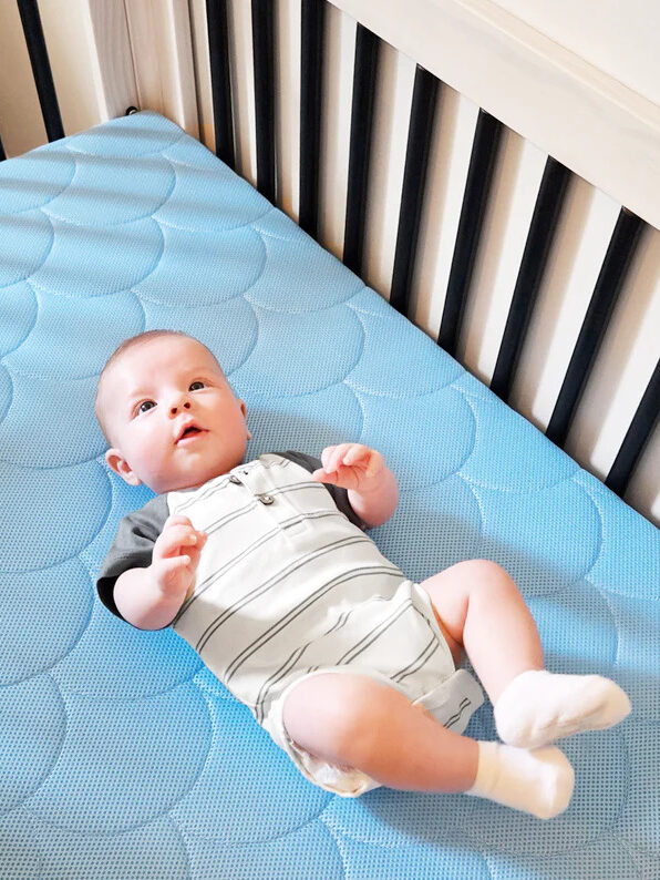 Baby laying on a blue Organic Dream Crib Mattress.