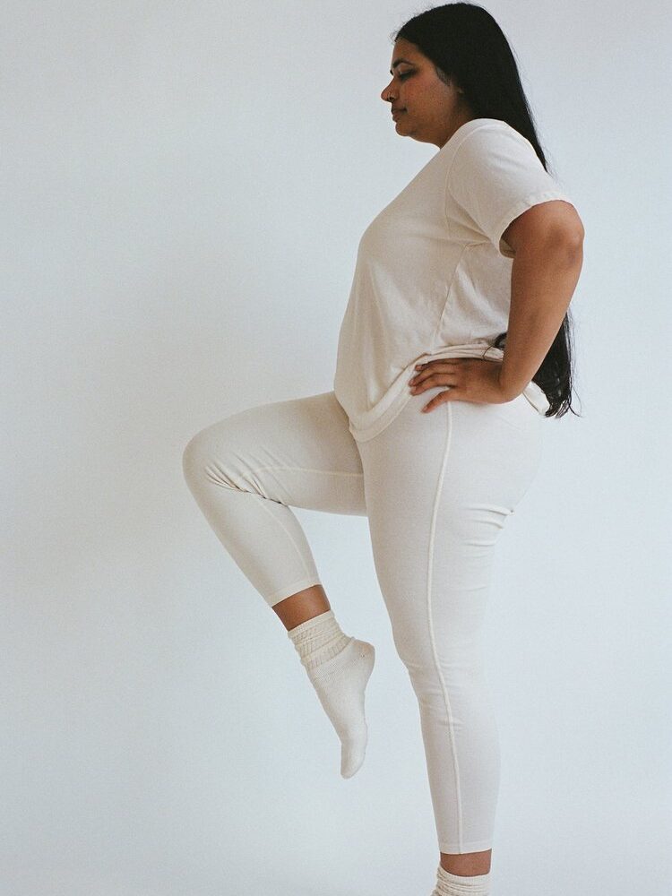 A model wearing Pansy organic cotton leggings in white. 