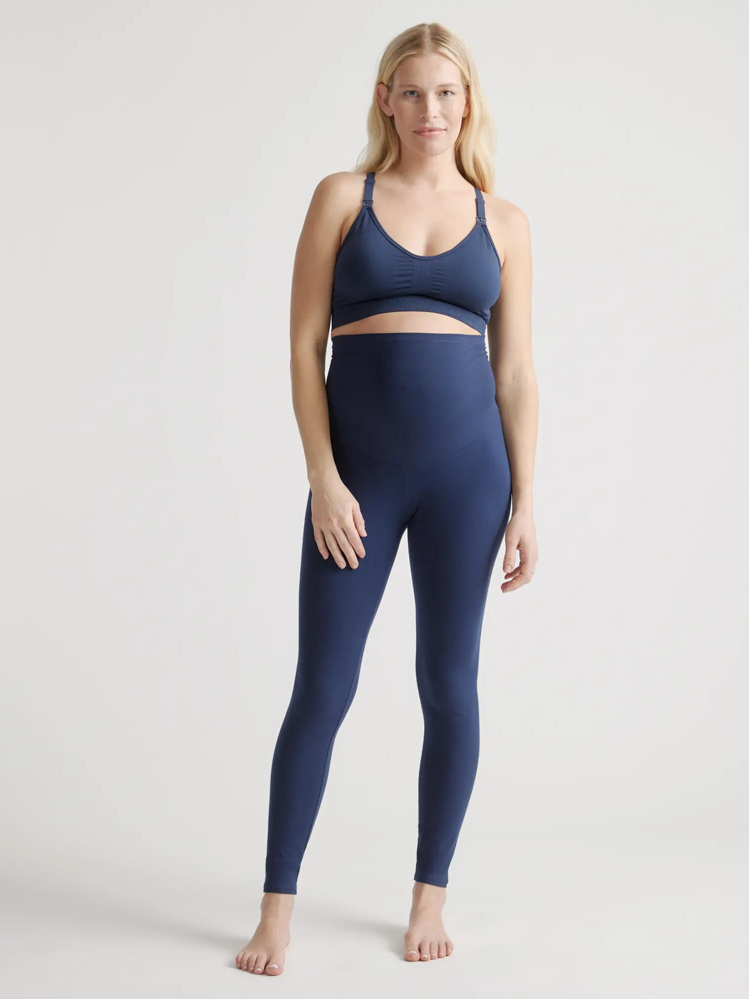 A model wearing Quince's navy organic maternity leggings.