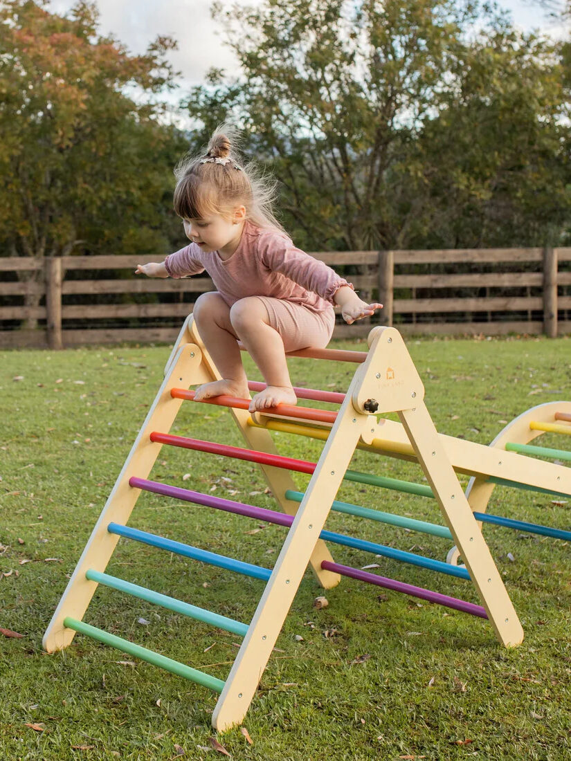 A child playing on a Tiny Land pickler triangle outside.