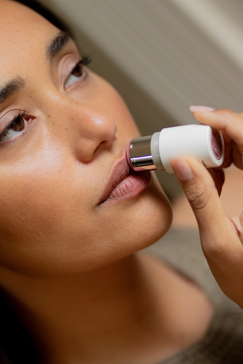A close-up of a woman applying lip balm.