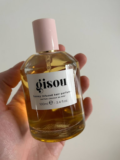The writer's hand holding the Gisou hair perfume. 
