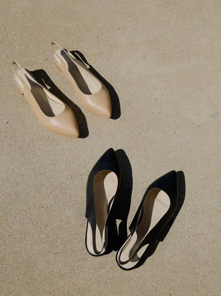 Two pairs of pointed-toe flats, one beige and one black, on a concrete surface.