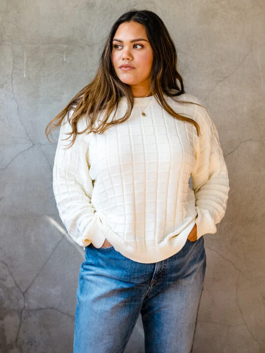 A model wearing a white sweater with a ribbed checker design from ABLE.