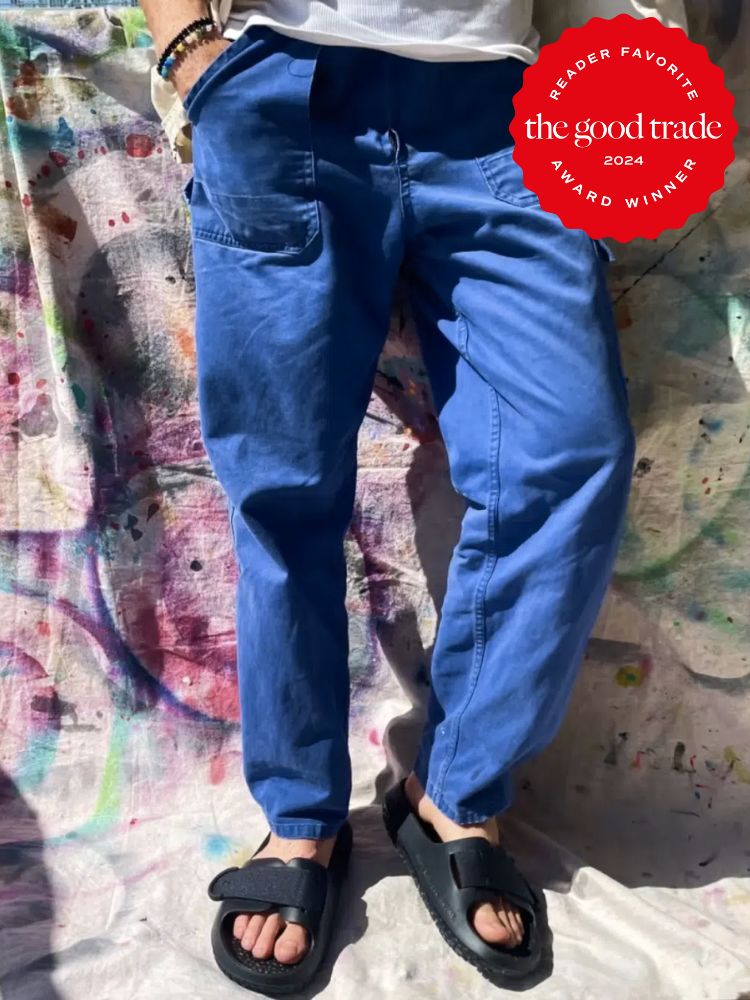The lower half of a person's body leans against a painted canvas drop cloth, wearing blue pants and black Allbirds sugar glider sandals. The TGT 2024 Award Winner Badge is on the right corner of the image. 