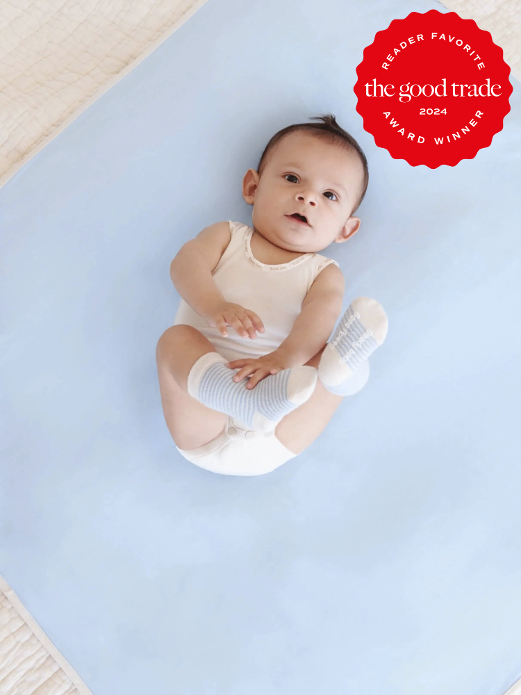 A baby wearing a white onesie tank and blue and white striped socks from Boody. The TGT 2024 Award Winner Badge is on the right corner of the image.