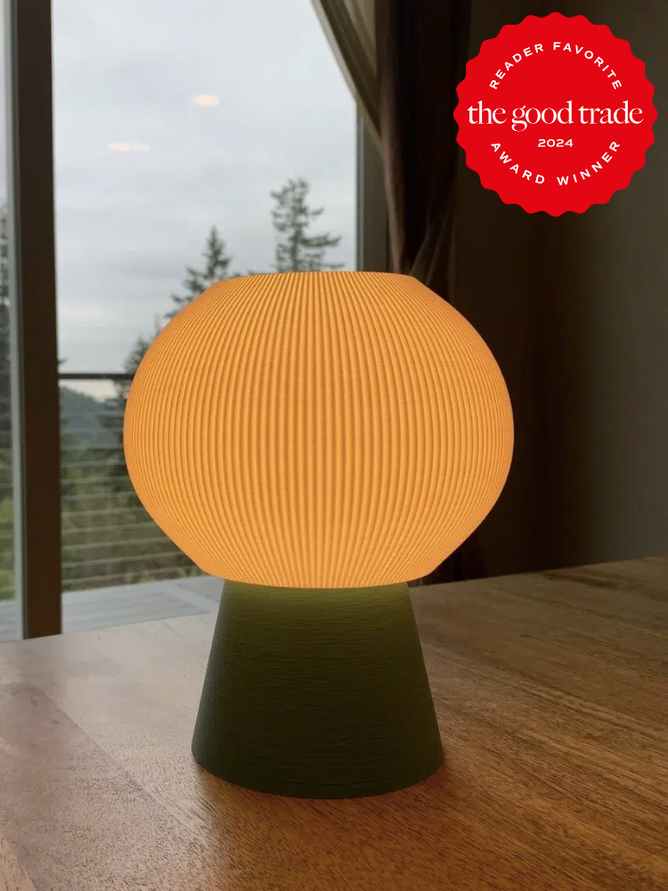 A green table lamp with a round ribbed circle lampshade glowing in orange on a counter. The TGT 2024 Award Winner Badge is on the right corner of the image.