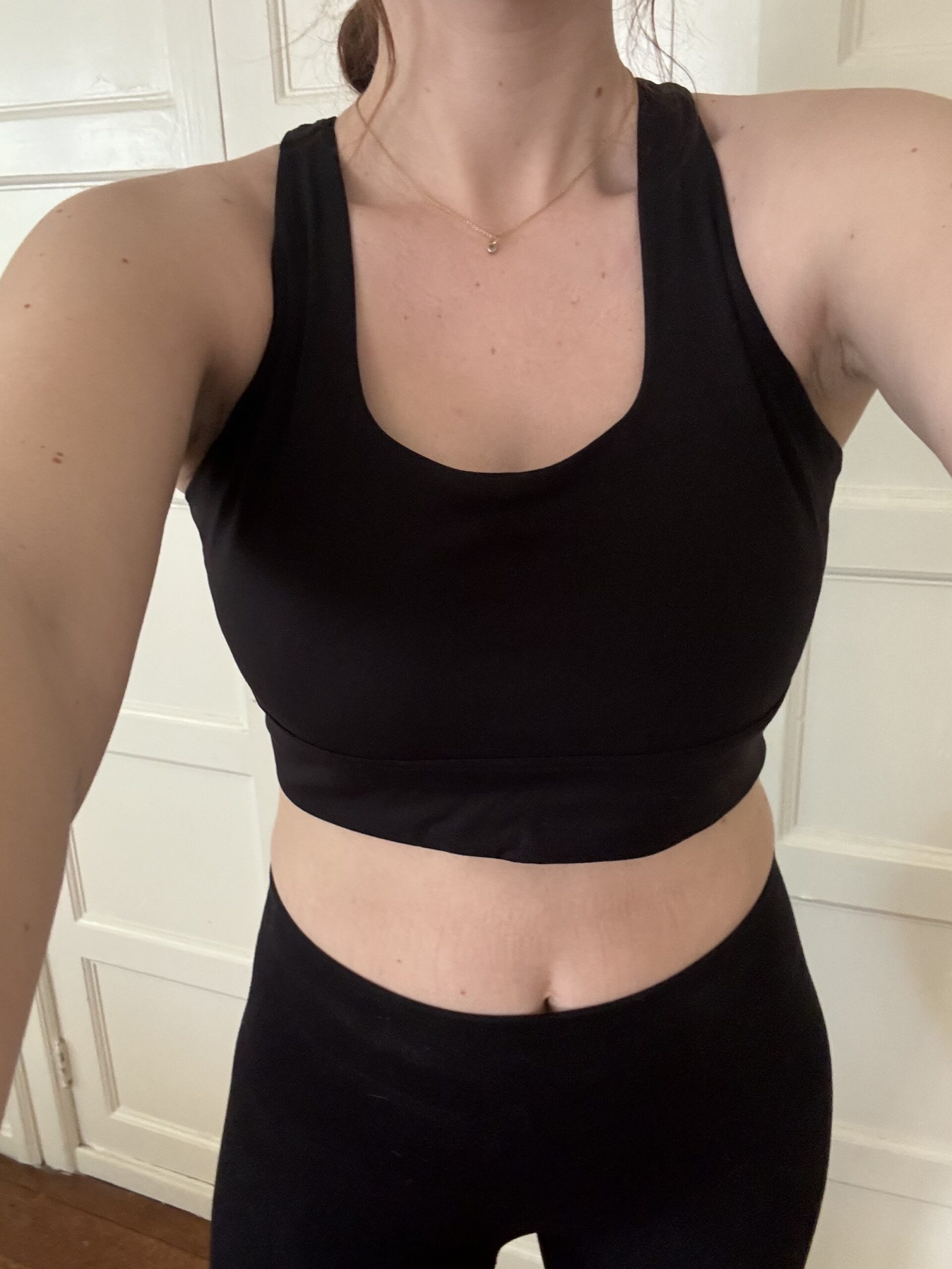 Woman wearing a black sports bra and leggings, close-up on torso.