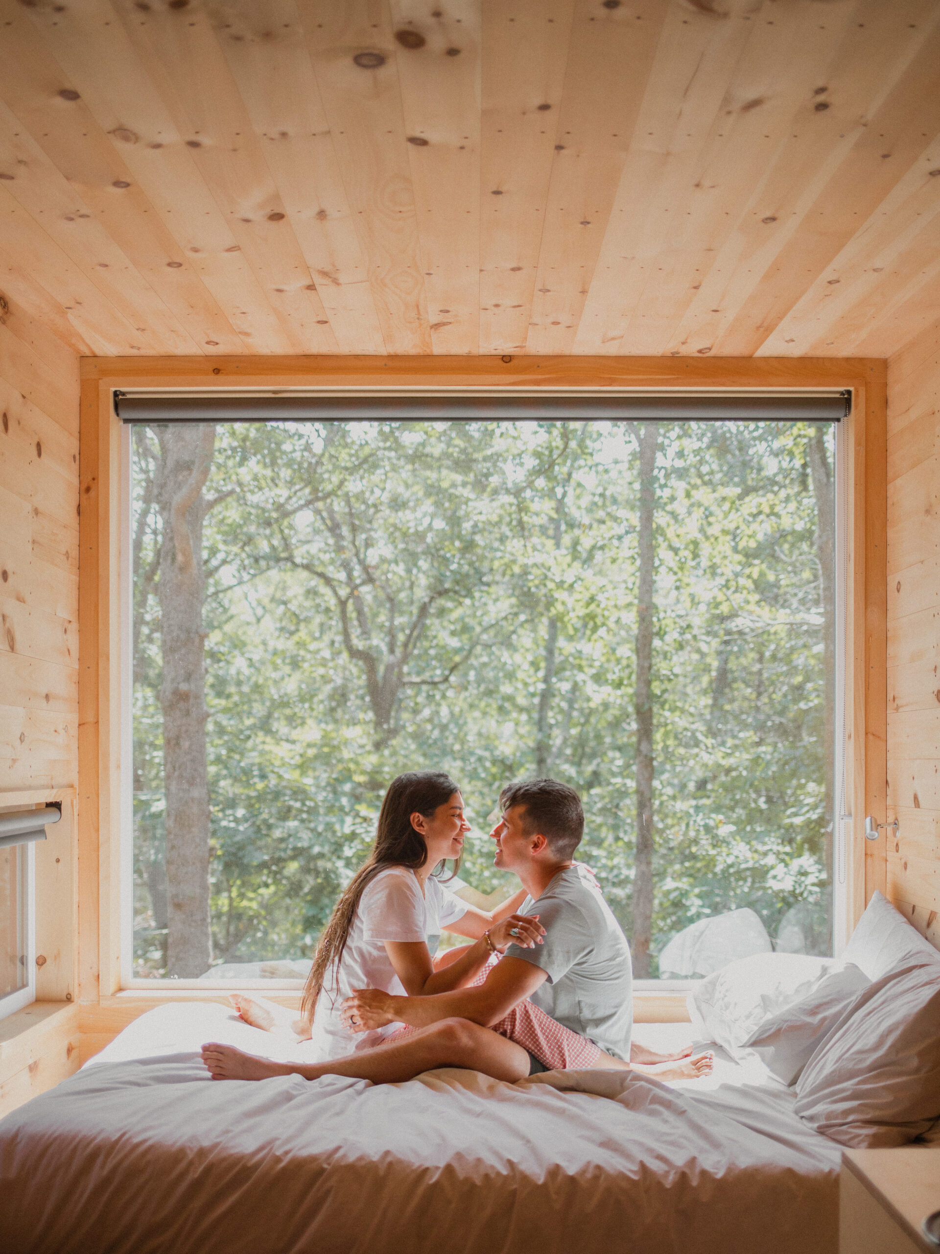 A couple snuggling on a bed in a Getaway Tiny Cabin.