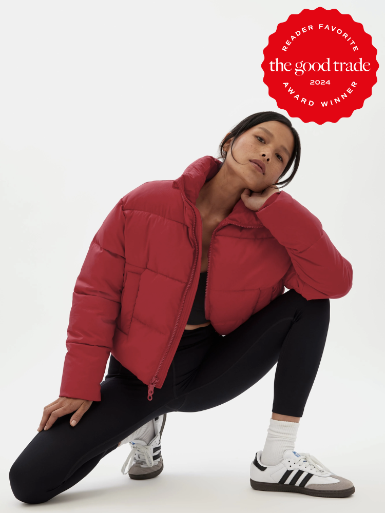 A model wearing a crop red recycled puffer coat by Girlfriend Collective. A red Reader Favorite Award 2024 sticker by The Good Trade is on the top right hand corner.