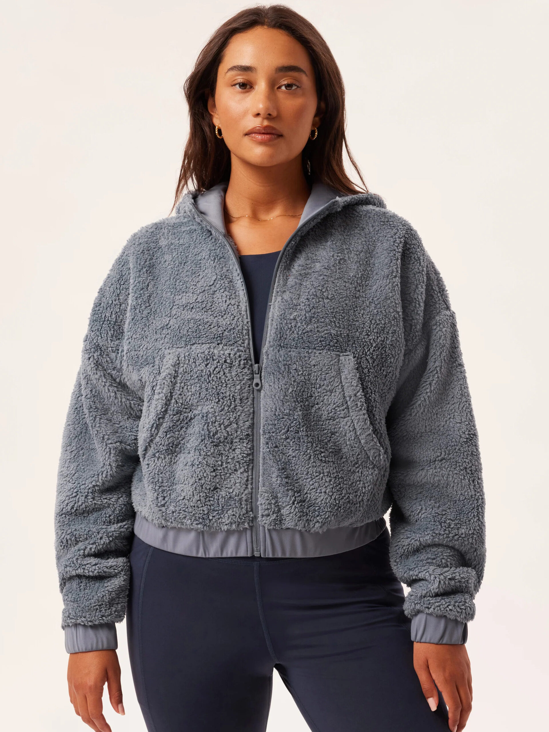 A model wearing a grey-blue fleece bomber from Girlfriend Collective.