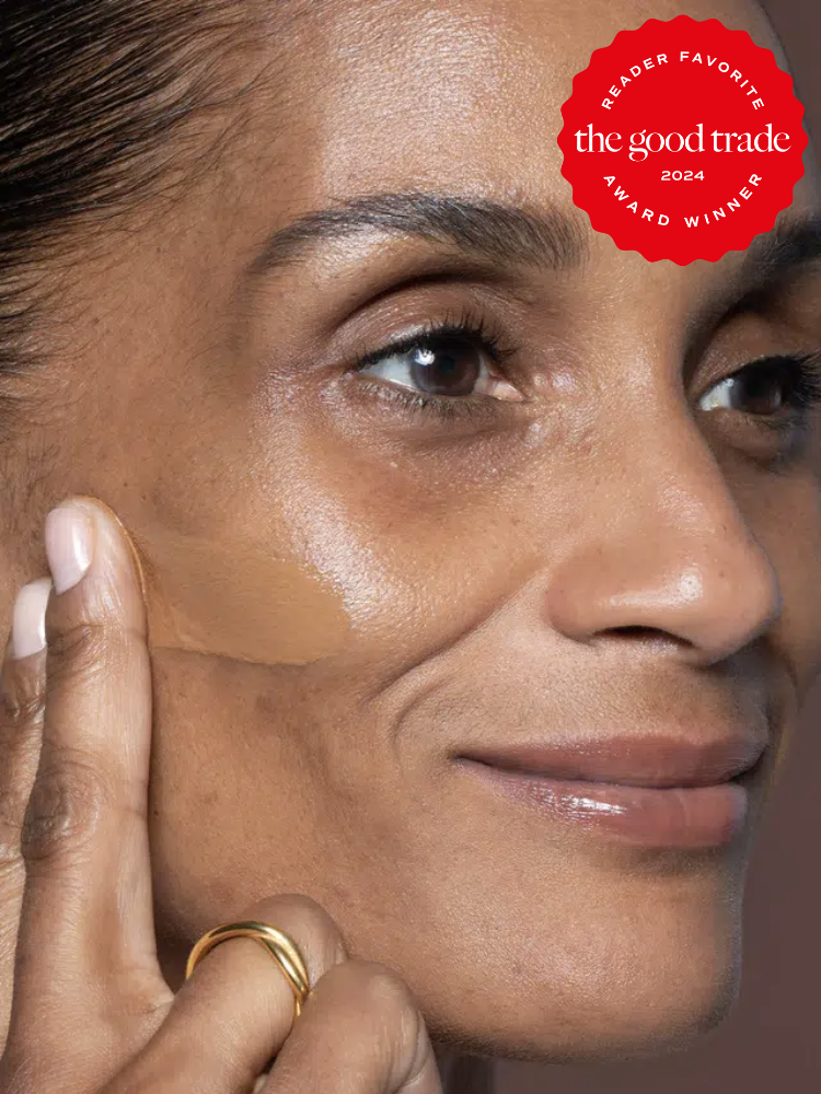 A model puts a swipe of Ilia foundation on her cheek. The TGT 2024 Award Winner Badge is on the right corner of the image. 