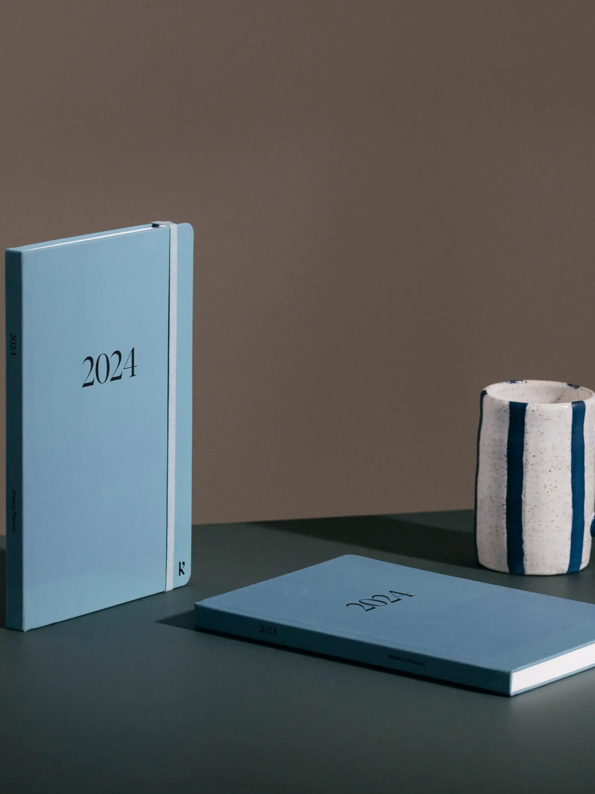 A studio shot of two 2024 planners by Karst next to a coffee mug.