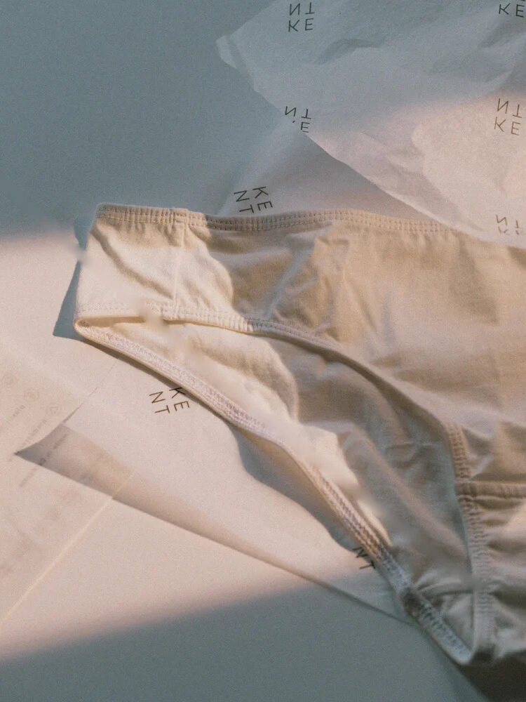 Close up of white KENT organic briefs, with the brand's packaging behind it.