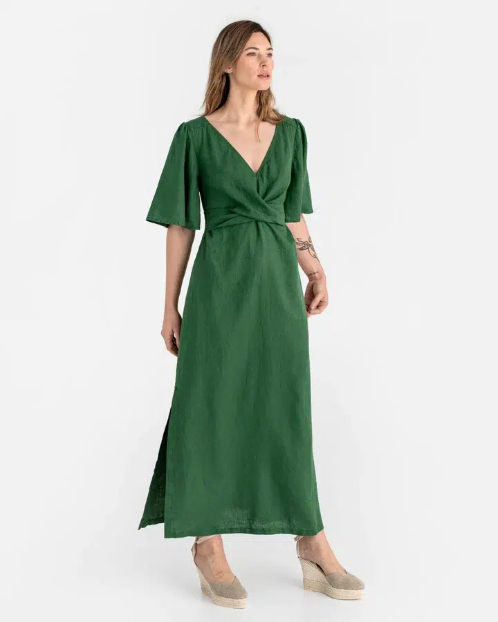 Woman posing in a green midi dress with short sleeves and a v-neckline.