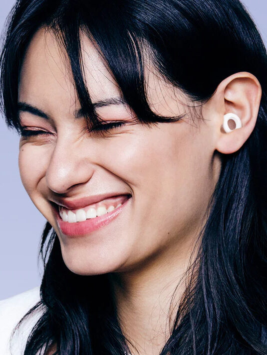 A model smiling wearing Loop earplugs.