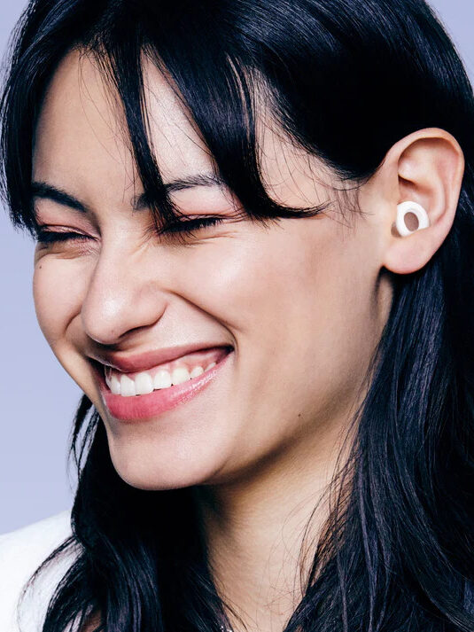 A model smiling wearing Loop earplugs. 