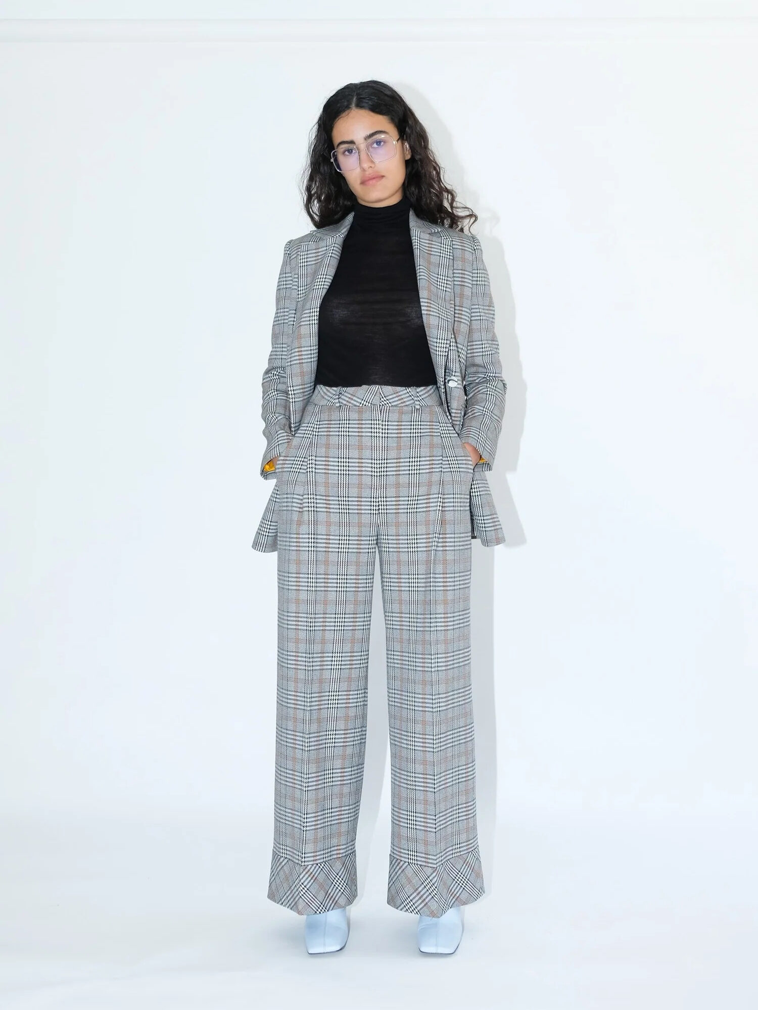 A model wearing a grey plaid pantsuit set from OhSevenDays. 
