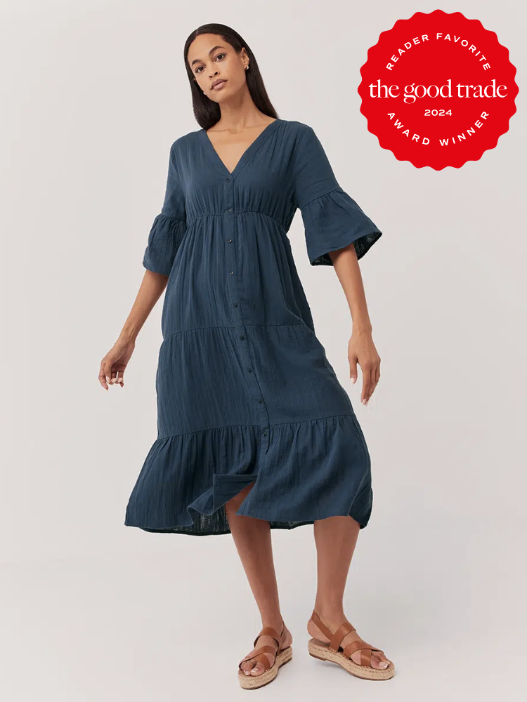 A model wears a long dark blue Pact summer dress. The TGT 2024 Award Winner Badge is on the right corner of the image. 
