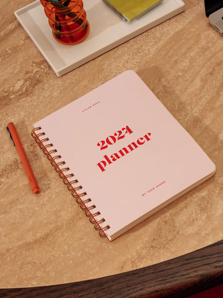 A light pink Papier 2024 planner with red lettering and accents.