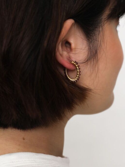 A close up shot of a model wearing the Winona gemstone hoops in red garnet from Penh Lenh. 
