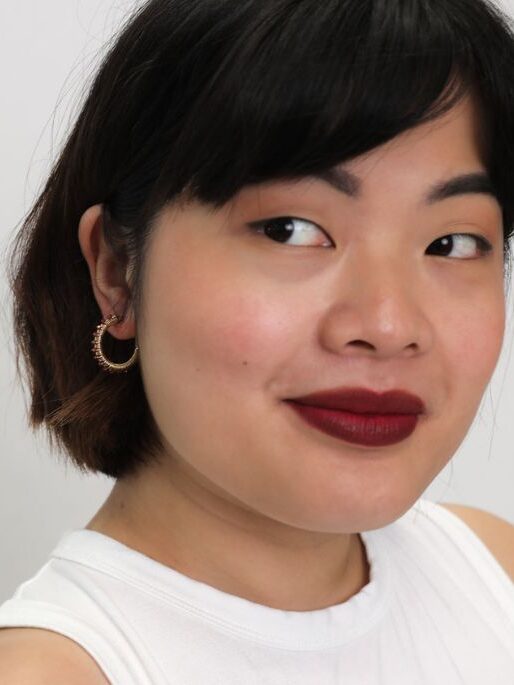 A close up shot of a model wearing the Winona gemstone hoops in red garnet from Penh Lenh. 