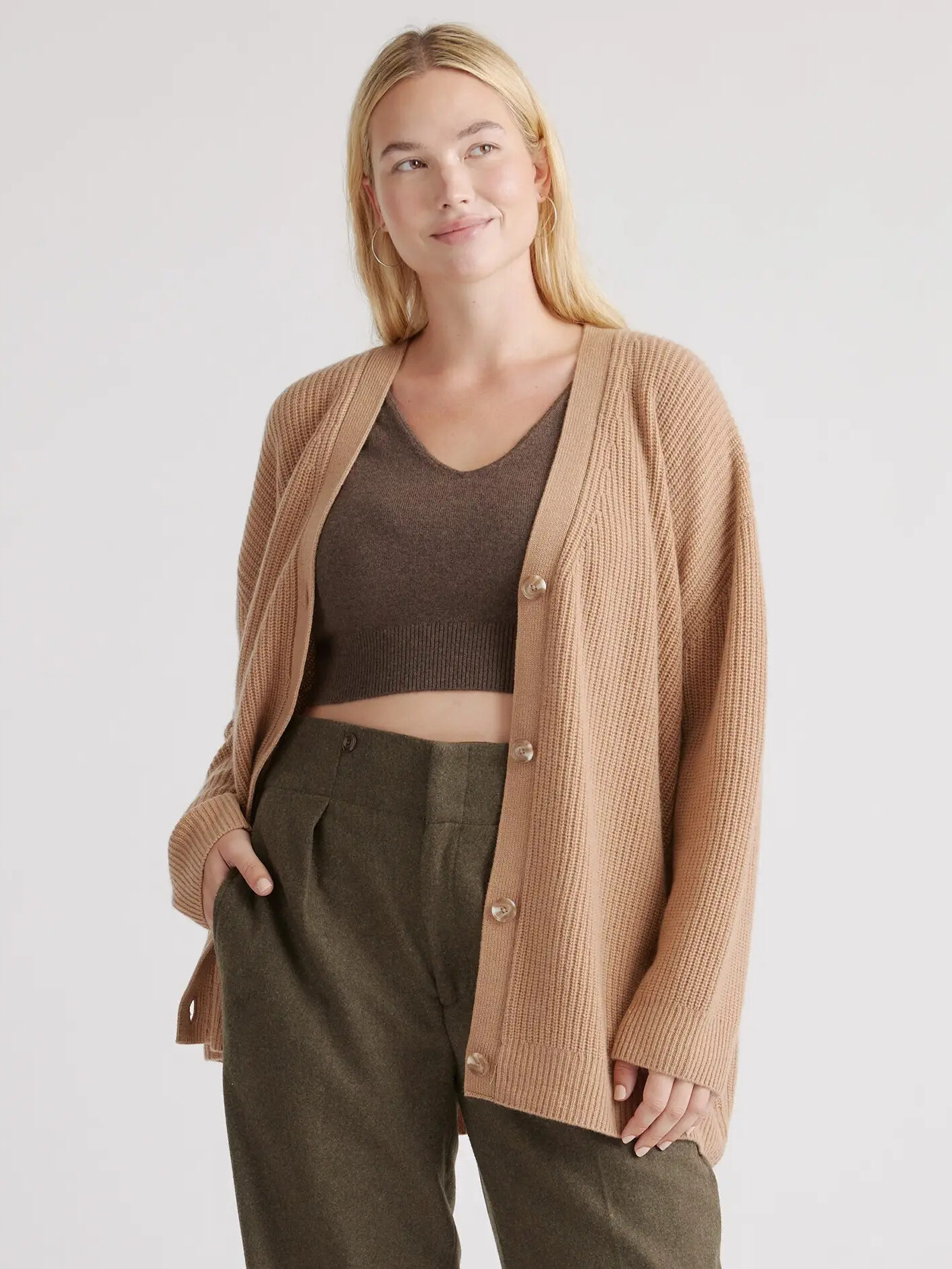 A model wearing a long beige cardigan from Quince.