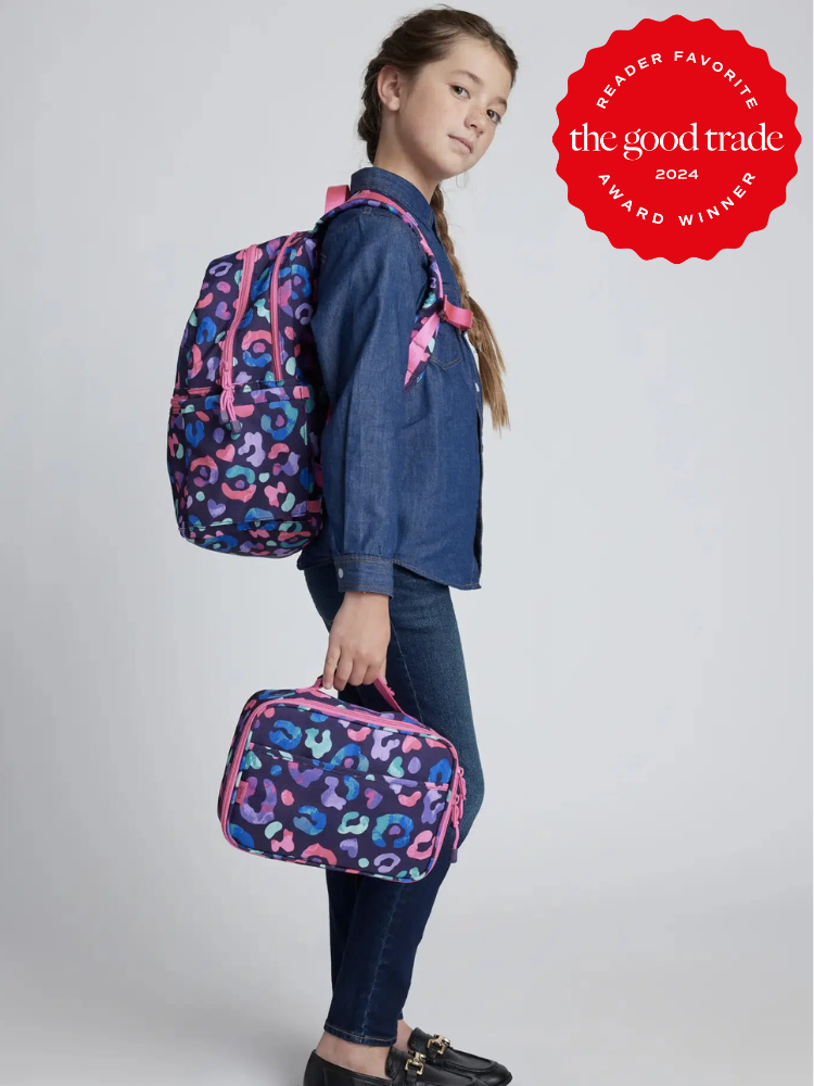 A young model wearing a Quince backpack and holding a Quince lunch bag. 
