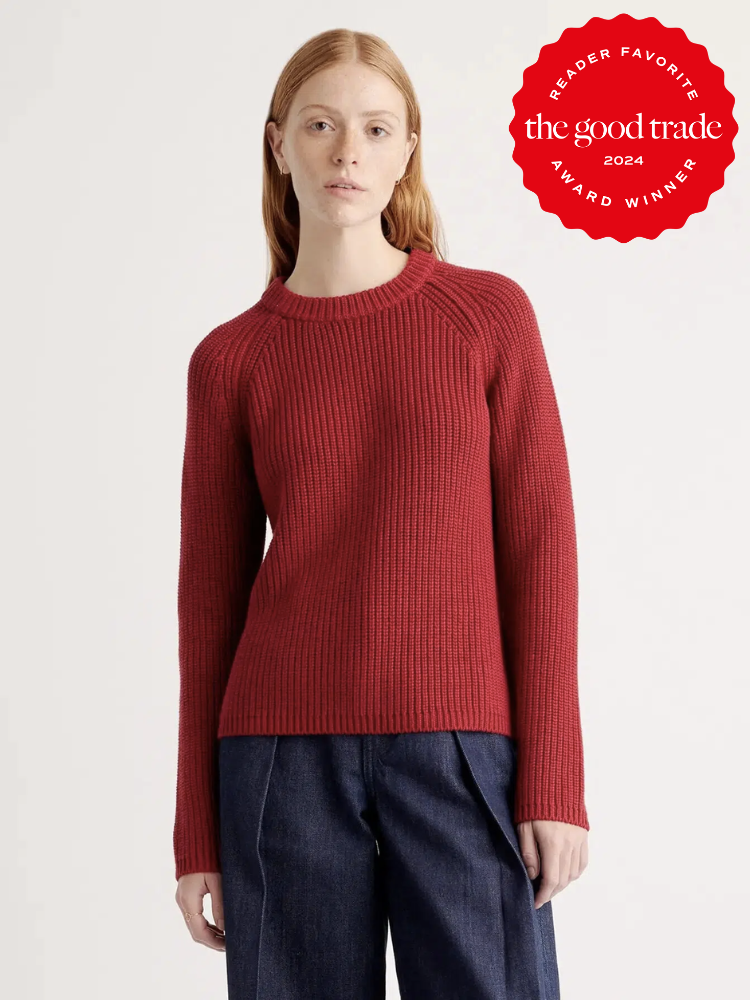 A model wearing a red Organic Cotton Fisherman Sweater by Quince.  The TGT 2024 Award Winner Badge is on the right corner of the image.