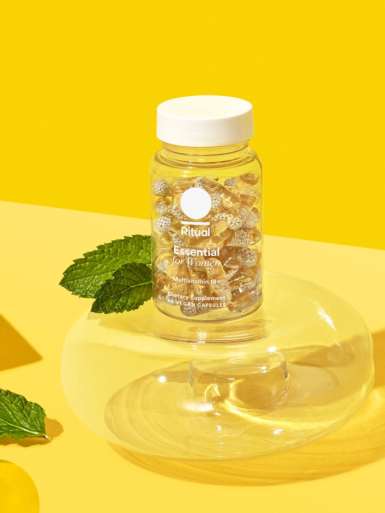 A bottle of Ritual Essential For Women Multivitamins in front of a yellow background.