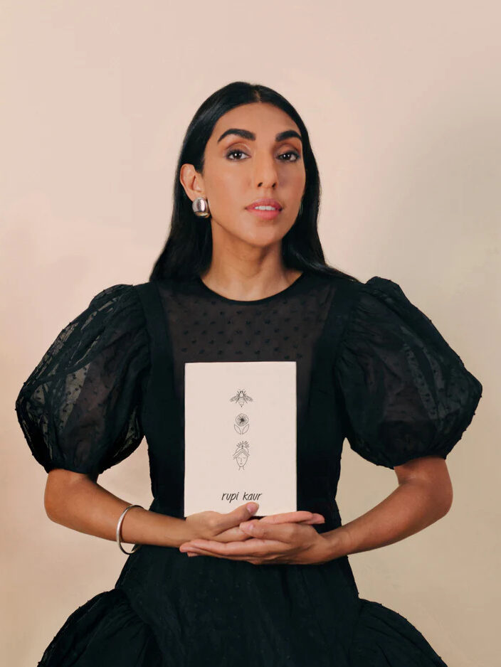 A portrait of Rupi Kaur holding her book.