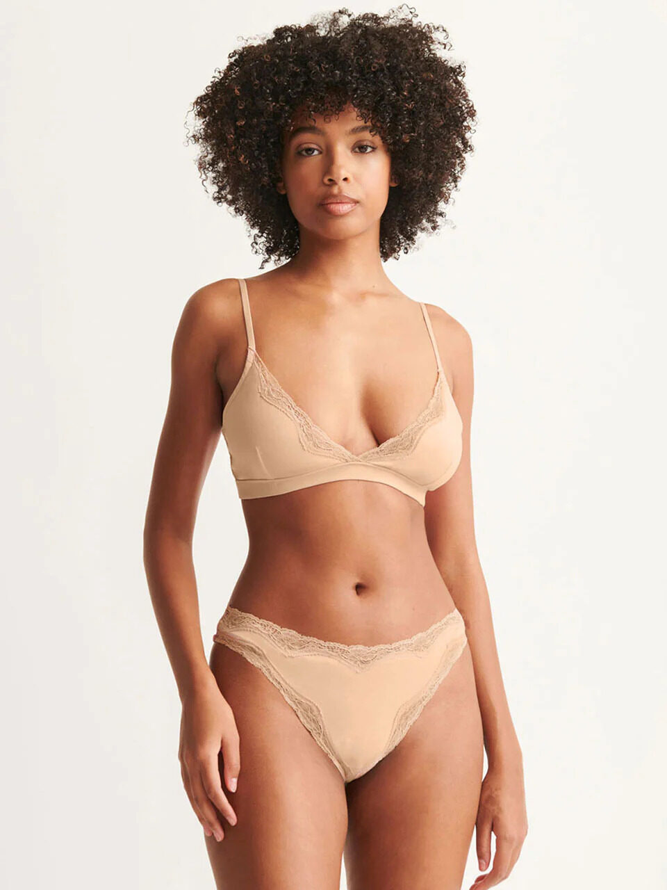 A model wearing a nude lace two piece organic bra and underwear set from Skin.