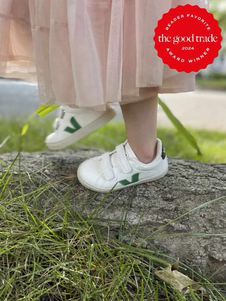 A close up of kid's feet on a log wearing Veja sneakers. The TGT 2024 Award Winner Badge is on the right corner of the image.