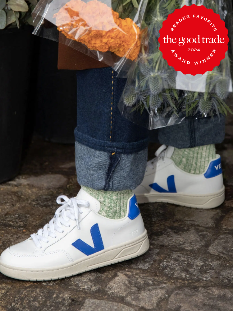 A cose up shot of a model wearing white and blue Veja sneakers. The TGT 2024 Award Winner Badge is on the right corner of the image. 
