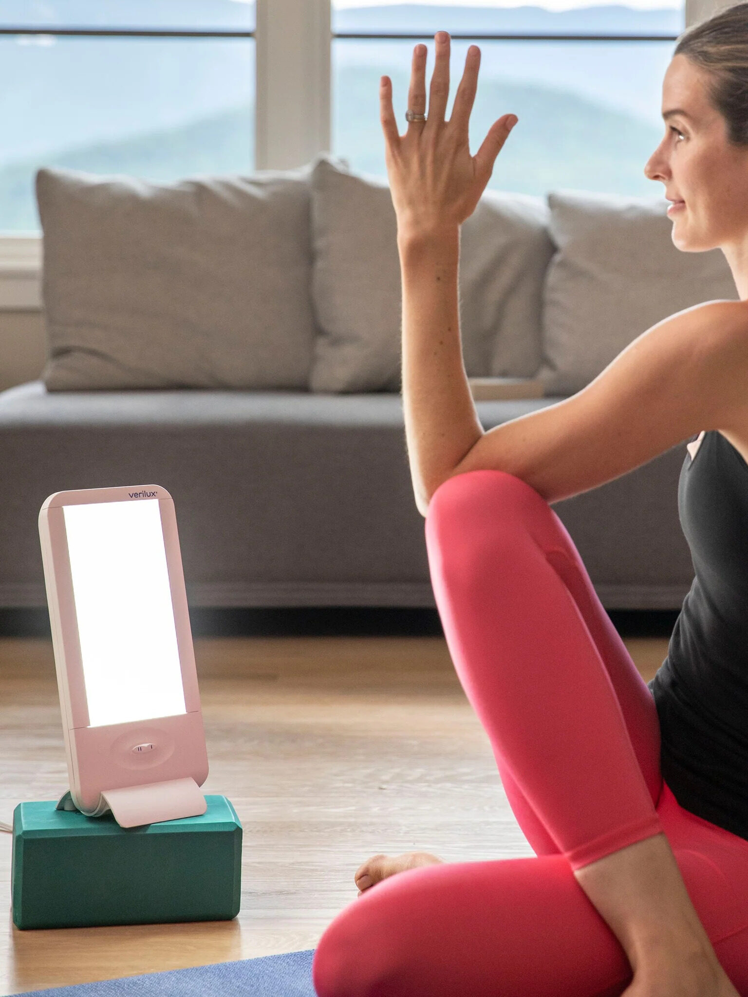A model doing yoga next to a Verilux lamp. 