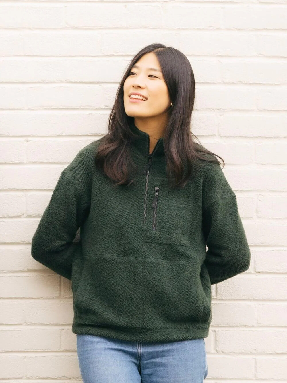 A model wearing a half zip green fleece sweater from Yes Friends.