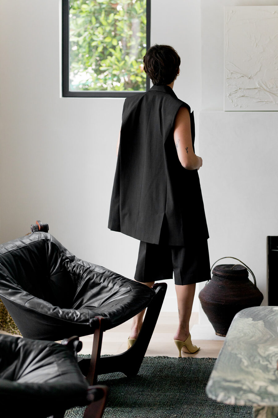 A woman wearing a black coat in a living room.