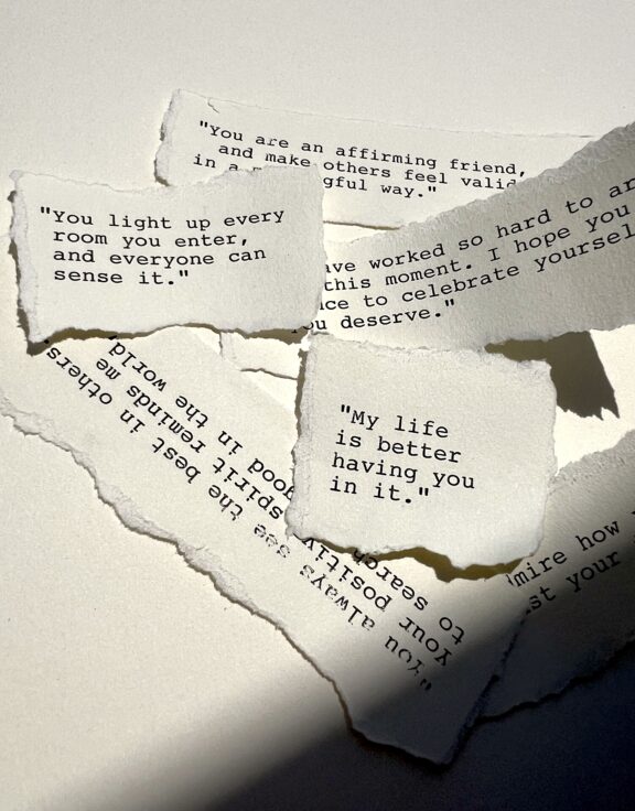 Torn pieces of paper with heartfelt handwritten messages on a white surface.