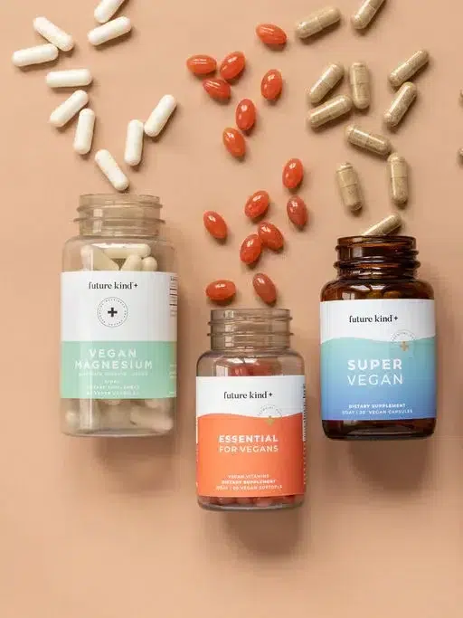 Three bottles of Future Kind vegan supplements laid down next to each other with the capsules spilling out the top of the bottles.
