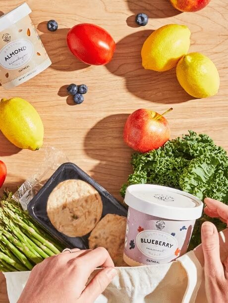 A variety of foods found in a Green Chef box spread across a wooden table.