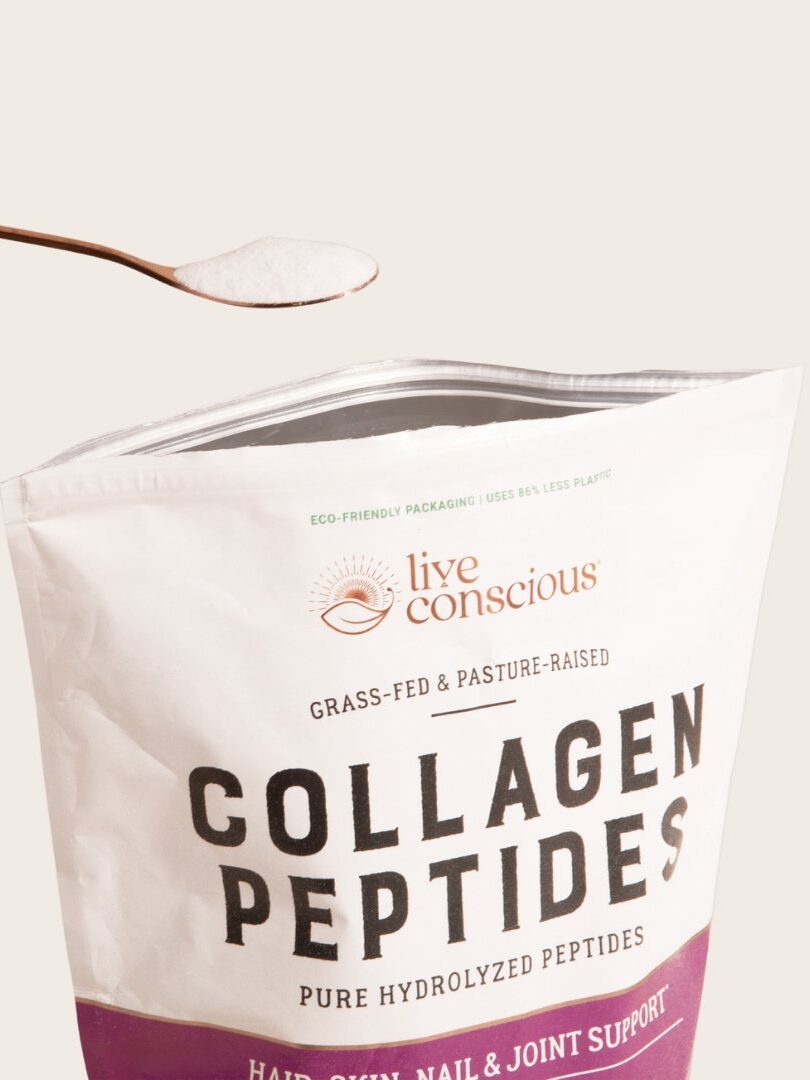 A open packet of Live Conscious collagen with a spoon of collagen powder hovering over it.