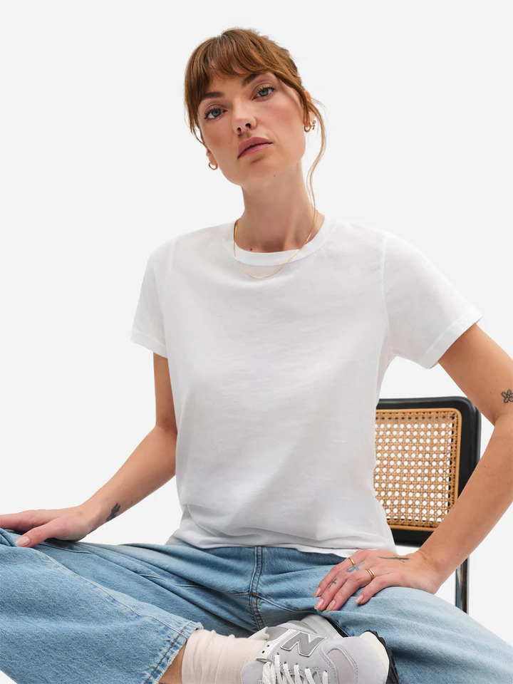 A woman is sitting on a chair wearing a white t - shirt and jeans.